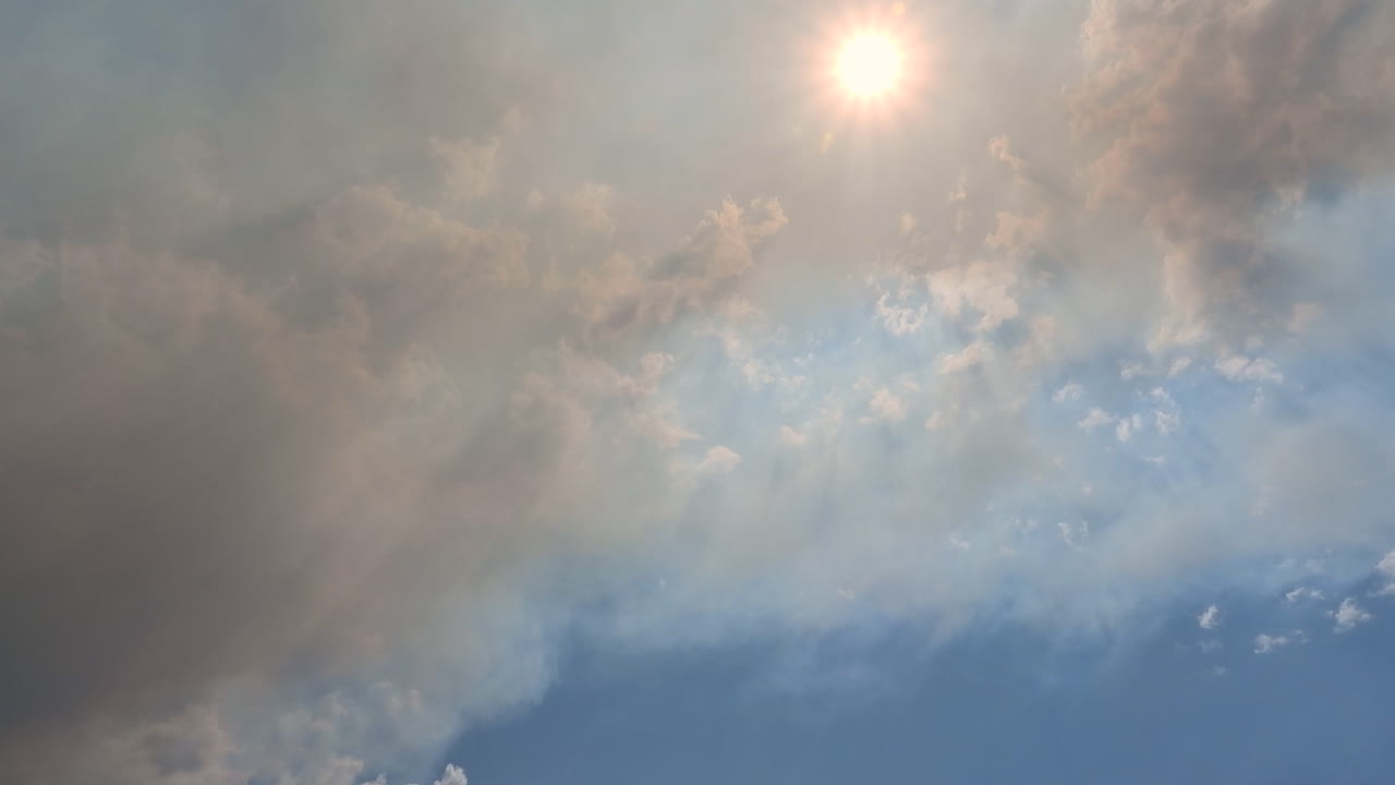 하늘과 태양 아래에서 움직이는 어두운 산불 연기, 대기 오염, 지구 온난화 및 기후 변화 개념