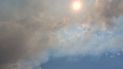 time lapse of dark wildfire smoke moving under sky and sun, air pollution, global warming and climate change concept