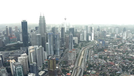 Vista-Aérea-De-La-Autopista-De-Kuala-Lumpur-Y-El-Horizonte-De-La-Ciudad,-Revelación-De-Inclinación-Hacia-Arriba