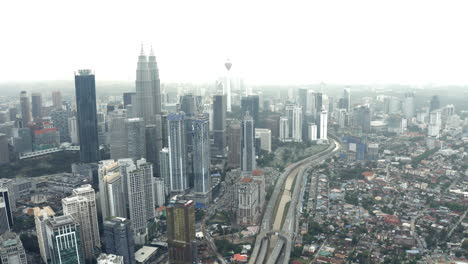 aerial view of kuala lumpur highway and city skyline, tilt up reveal