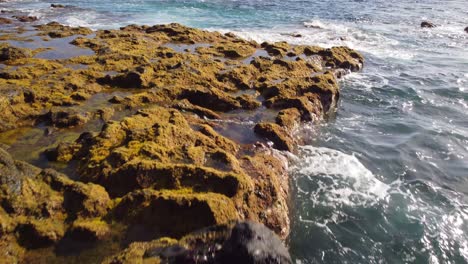 Foamy-ocean-water-hits-rocky-coastline-of-Canary-islands,-aerial-view