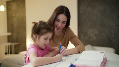 madre y su hija en edad preescolar hacen la tarea juntos en casa