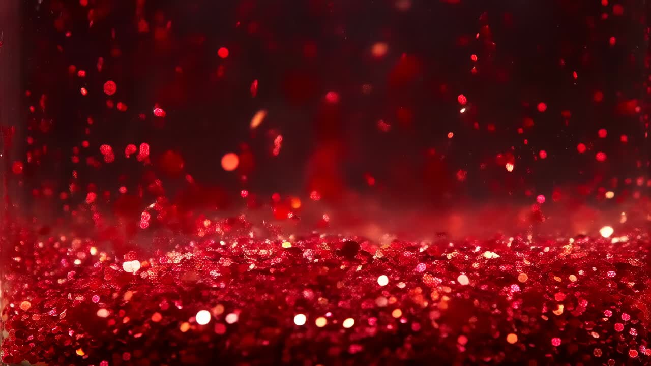Lifting red glitter flakes floating upward from bed after air pulse in studio macro, with bokeh