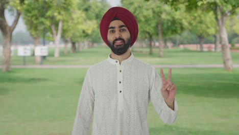 sikh indian man showing victory sign in park