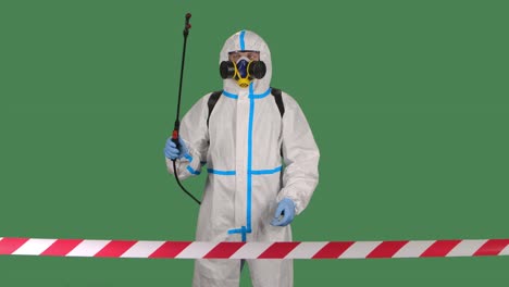 virólogo en uniforme de protección camina y desinfecta un área peligrosa cercada con una cinta de señal roja y blanca. aislado en una pantalla verde clave de croma. cámara lenta. primer plano