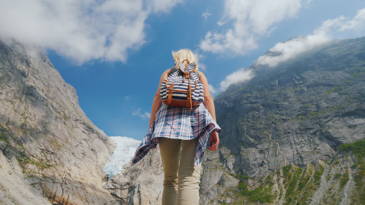 una mujer sana levantó las manos con alegría de pie en el fondo del glaciar brixdal en noruega