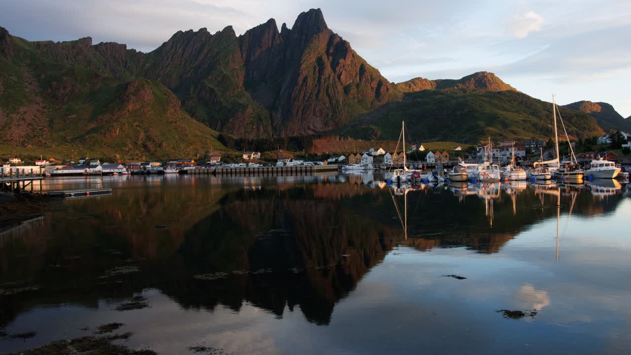 Marina by the mountain and their reflection in water in early morning; rapid light change due to sunlight blocking by clouds. Time Lapse. lofoten Islands, Northern Norway