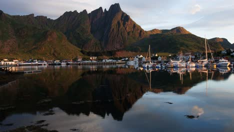 marina by the mountain and their reflection in water in early morning; rapid light change due to sunlight blocking by clouds. time lapse. lofoten islands, northern norway