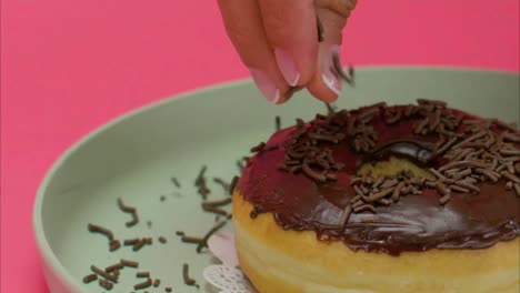 chocolate being sprinkled on a donut by a women chef