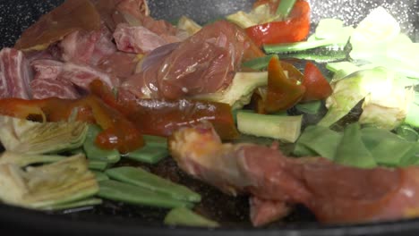 fresh meat and vegetables cooking in a paella dish in slow motion