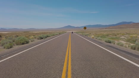 Amerikas-Einsamster-Highway,-Gefilmt-Aus-Der-Mitte-Der-Straße,-Als-Ein-Großes-Zwillingsmotorrad-Losfährt-Und-In-Der-Ferne-Verschwindet