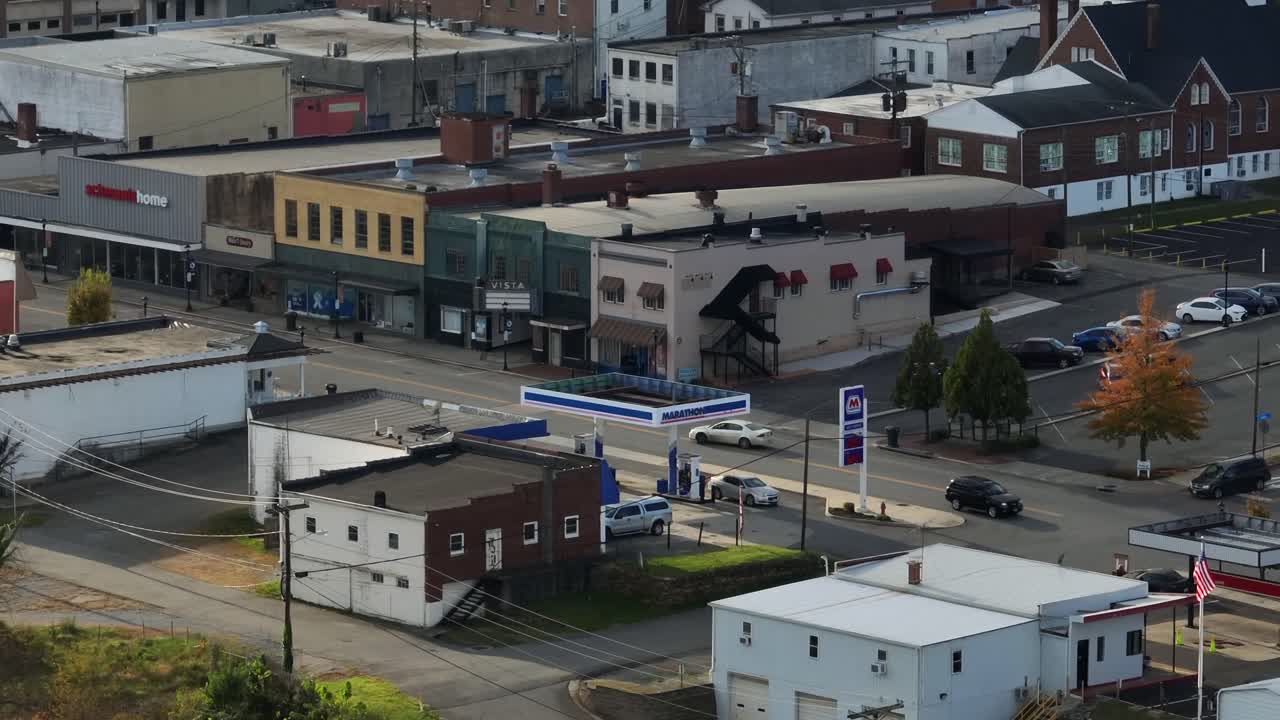 Aerial zoom of historic american town with gas station and old houses. Daytime in city of Virginia. Driving cars on main street. Wide shot.