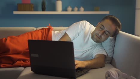 el hombre que usa la computadora portátil acostado se queda dormido.