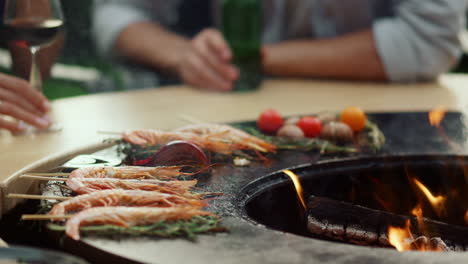 모르는 사람들이 바 ⁇ 에서 bbq 그릴에 음식을 요리하고 있습니다. 파티를 준비하는 새우
