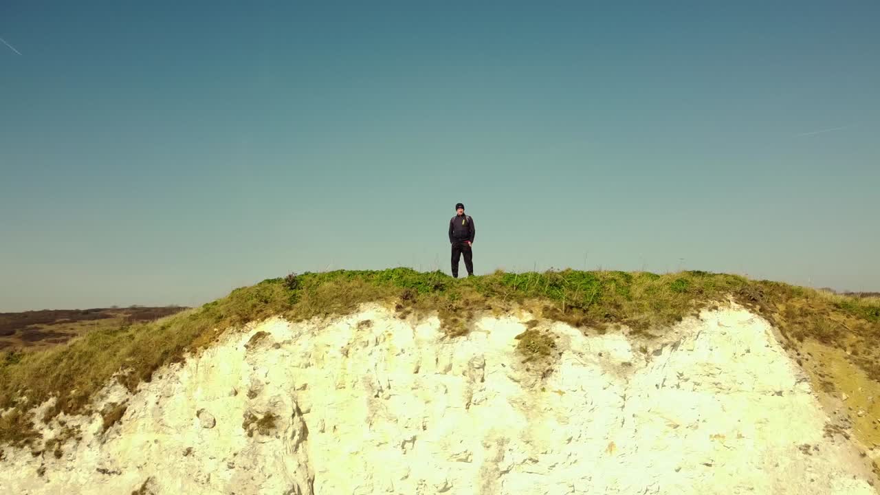 A man standing on a cliff overlooking the coast