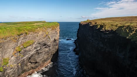 timelapse from the cliff edge captures the atlantic ocean, dramatic cliffs in shadow and sunlight, and distant figures walking