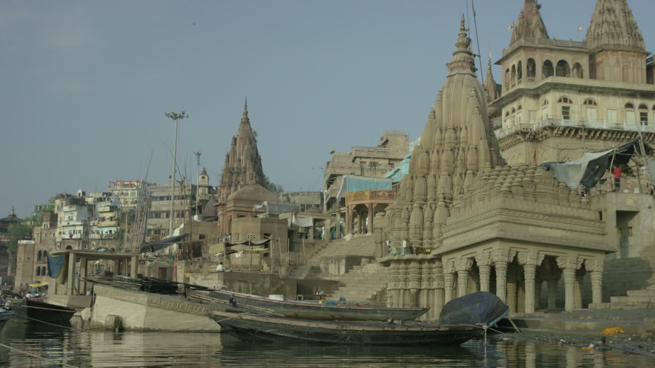 A bird flies past the city and lands on a boat by the shore