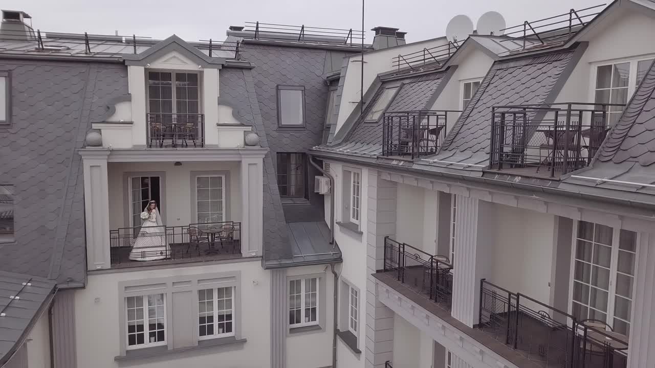 Brud står på en balkon i en hvid brudekjole
