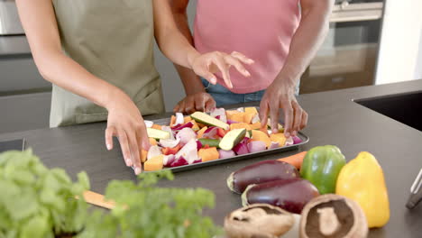 preparing vegetables on baking tray, couple cooking together in modern kitchen
