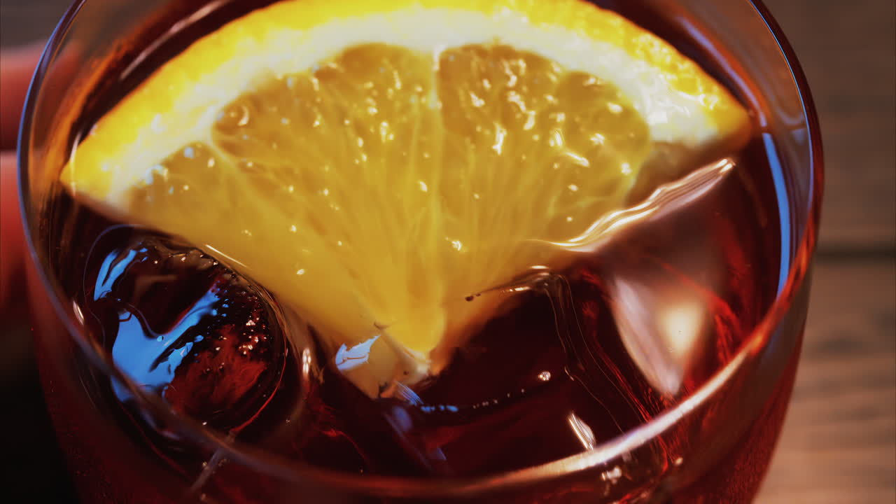 Primo piano di un cocktail Negroni con fetta d'arancia e cubetti di ghiaccio su un tavolo di legno