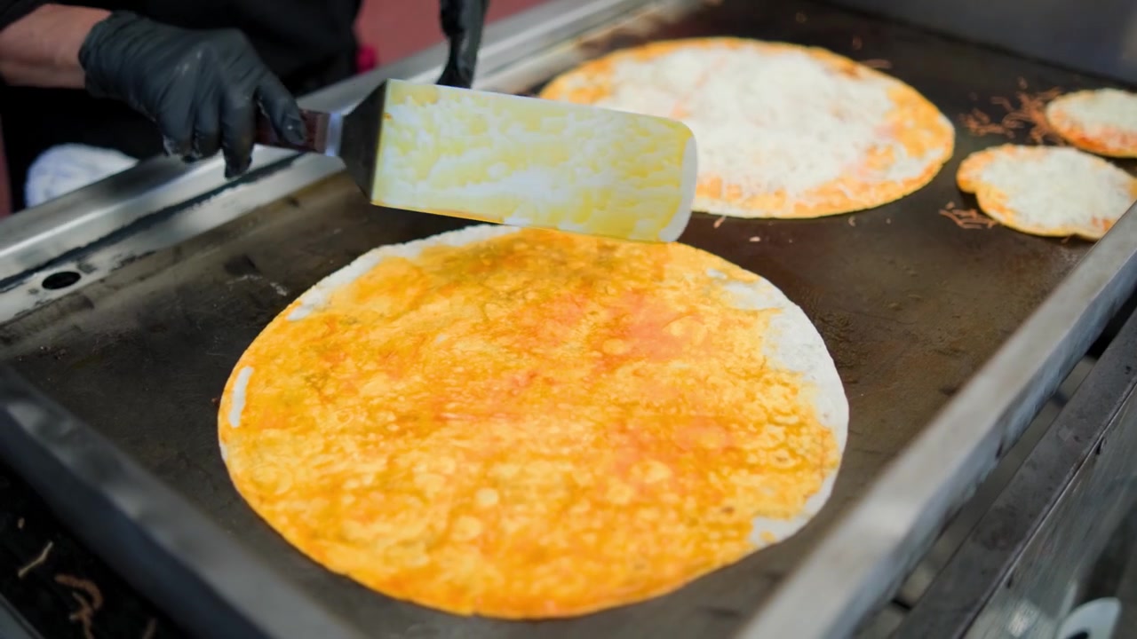 Commercial kitchen footage showing birria pizza in the making during preparation of a savory birria pizza on a flat grill