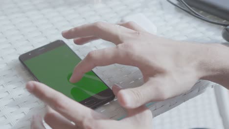 person using a smartphone with a green screen