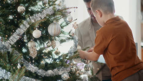 father and son decorate the christmas tree together