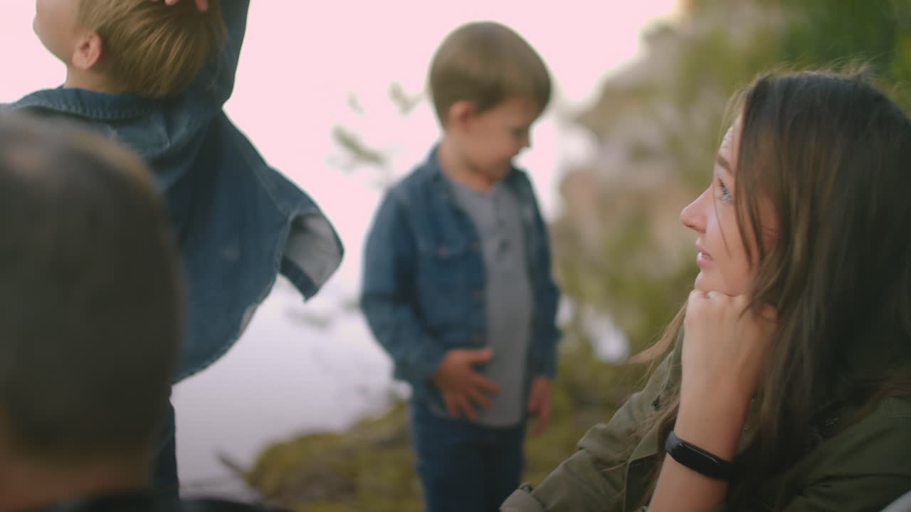 공원이나 보호구역에서 자연에서 가족 주말 기쁜 아이들과 편안한 부모들은 숲의 호수 연안에서 휴식을 취하고 있습니다.