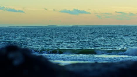 ocean and seashore beach view behind the rocks in the evening sunset time afterglow with waves, water and sun