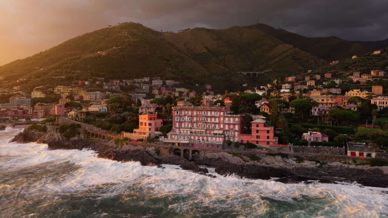 Slow motion aerial view of coastal town at sunset with dramatic sky