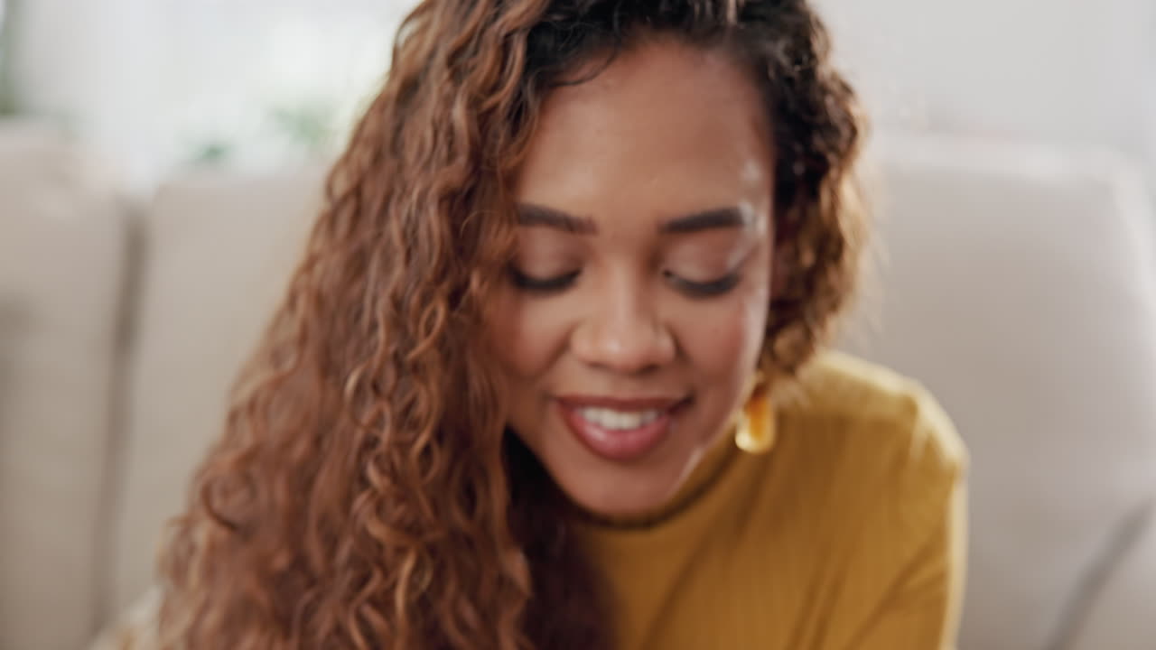 Woman Sitting on a Couch, Smiling and Looking at Her Phone
