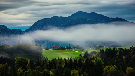 low wispy cloud drifts over green valley in the austrian alps