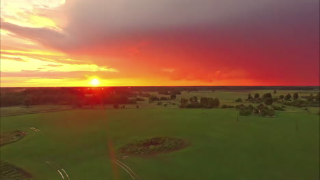 Puesta-De-Sol-Roja-Vibrante-Sobre-Campos-Agrícolas,-Vista-Aérea-De-Drones