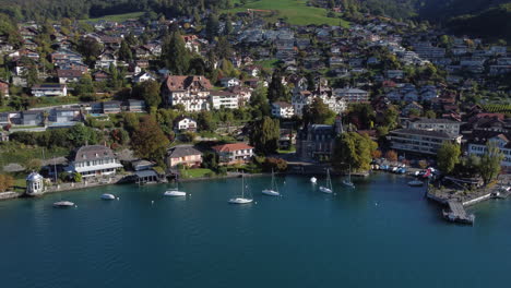 Fantástica-Toma-Aérea-De-La-Costa-Del-Municipio-De-Oberhofen-En-Suiza,-En-Un-Día-Soleado