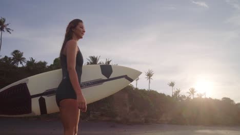 Hermosa-Mujer-Deportiva-Sosteniendo-Su-Tabla-De-Surf-Y-Caminando-En-Una-Playa-De-Arena