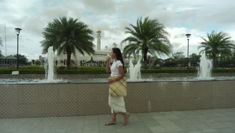 beautiful  asian young woman with natural bag walking on pavement close to fountain