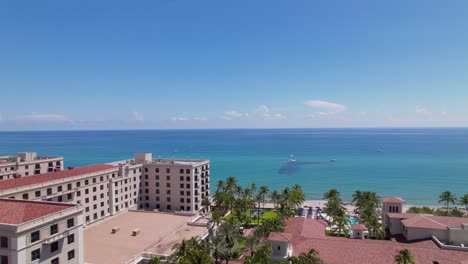 Drone-passing-by-building-to-water-aerial-view-of-west-palm-beach-skyline-downtown-area-and-beautiful-beach-sand-and-boats-in-water