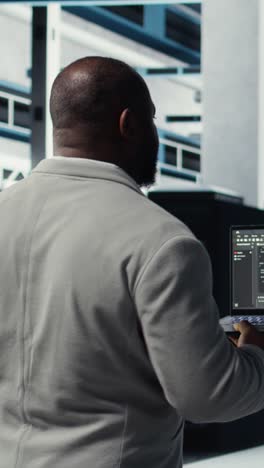 vertical video data center computer scientist coding on laptop, doing software updates