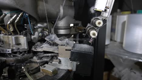 the process of manufacturing of socks on a loom - close-up parts of the machine with threads, the production process in a garment factory