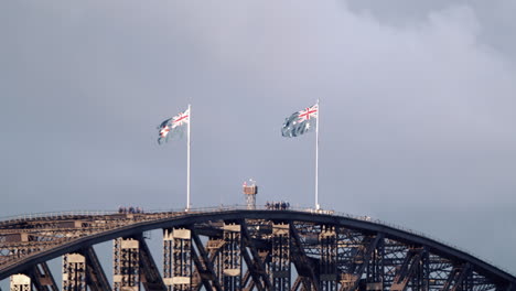 australian and state flag on harbour bridge against overcast sky in sydney nsw, australia - static shot