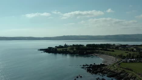 Aerial-dolly-in-of-sea-coast-at-day,-lighthouse-in-background