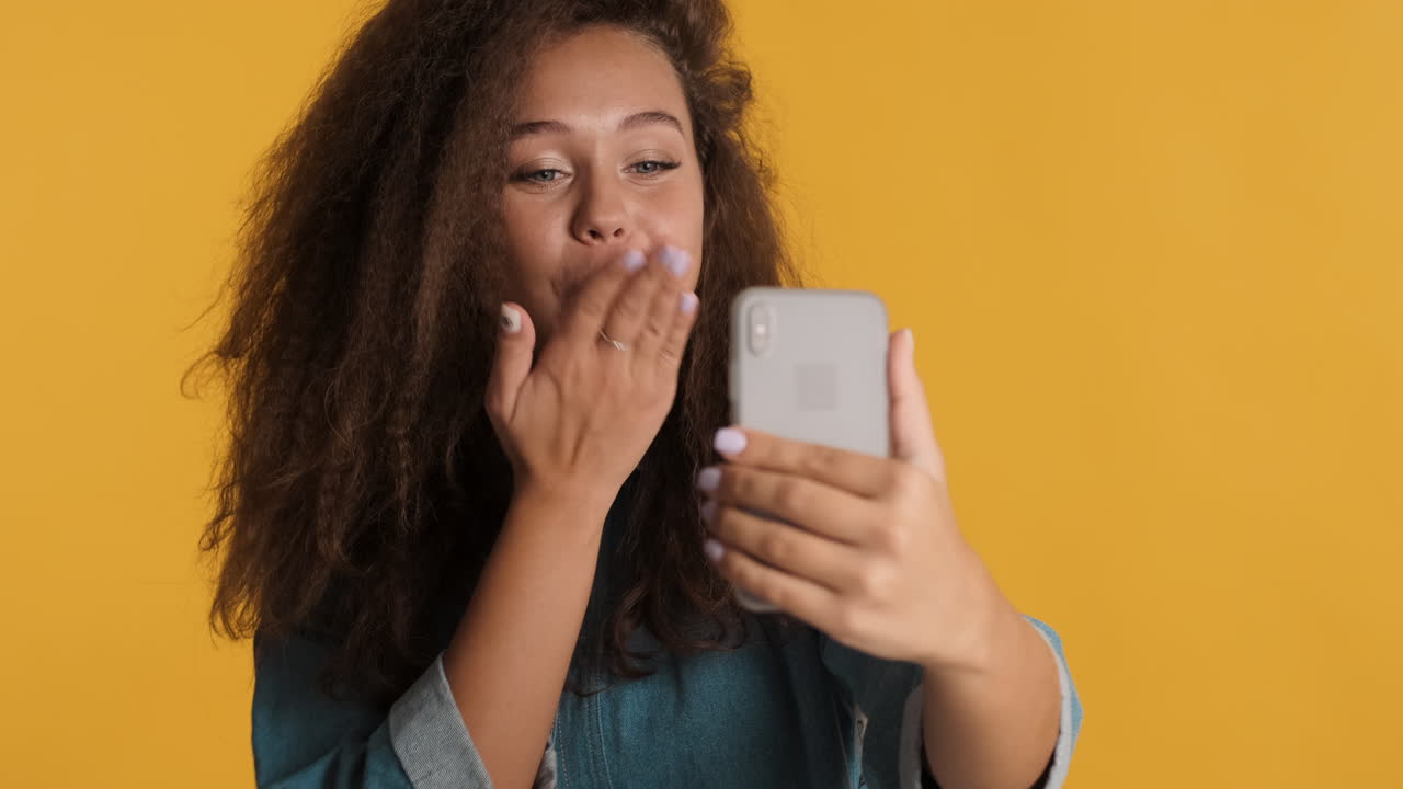 Caucasian curly haired woman video calling on smartphone.