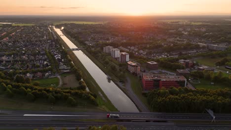 aerial view of a city with a canal, highway, and residential areas at sunset