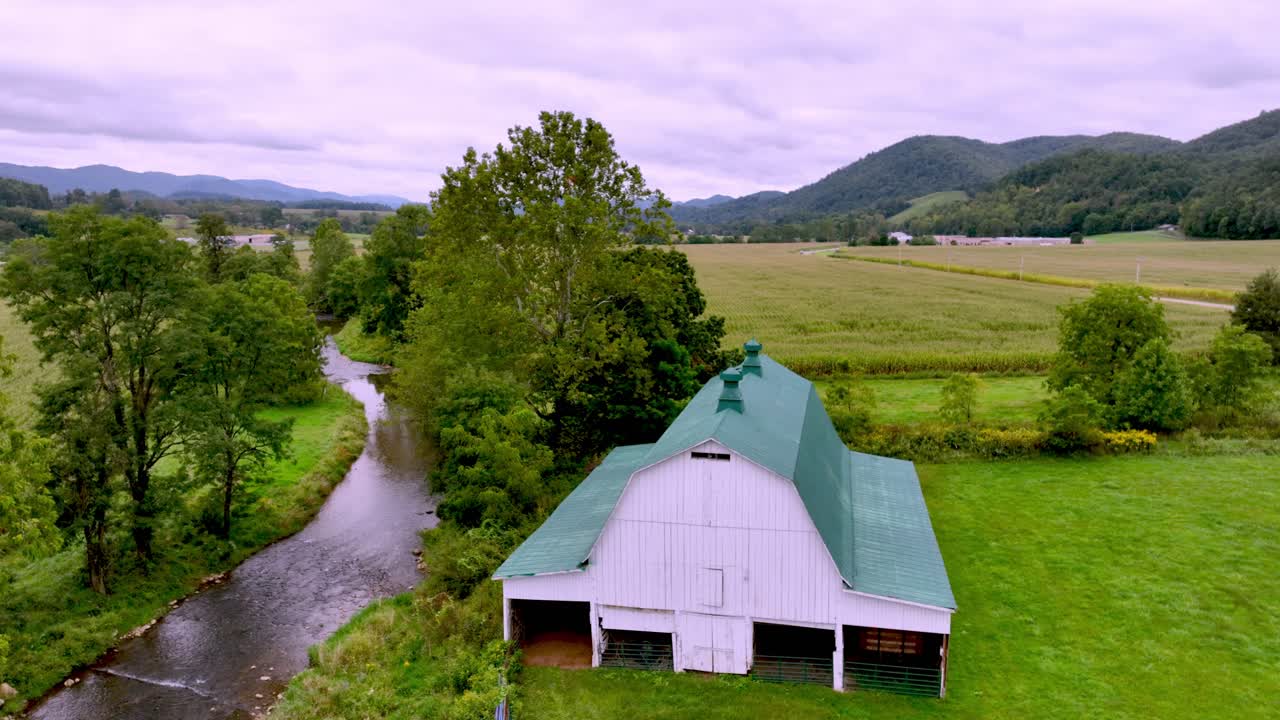 Luftoptagelse, der bevæger sig over en lade med landbrugsjord og bjergkulisse over en gård i Appalachia nær Mountain City, Tennessee.