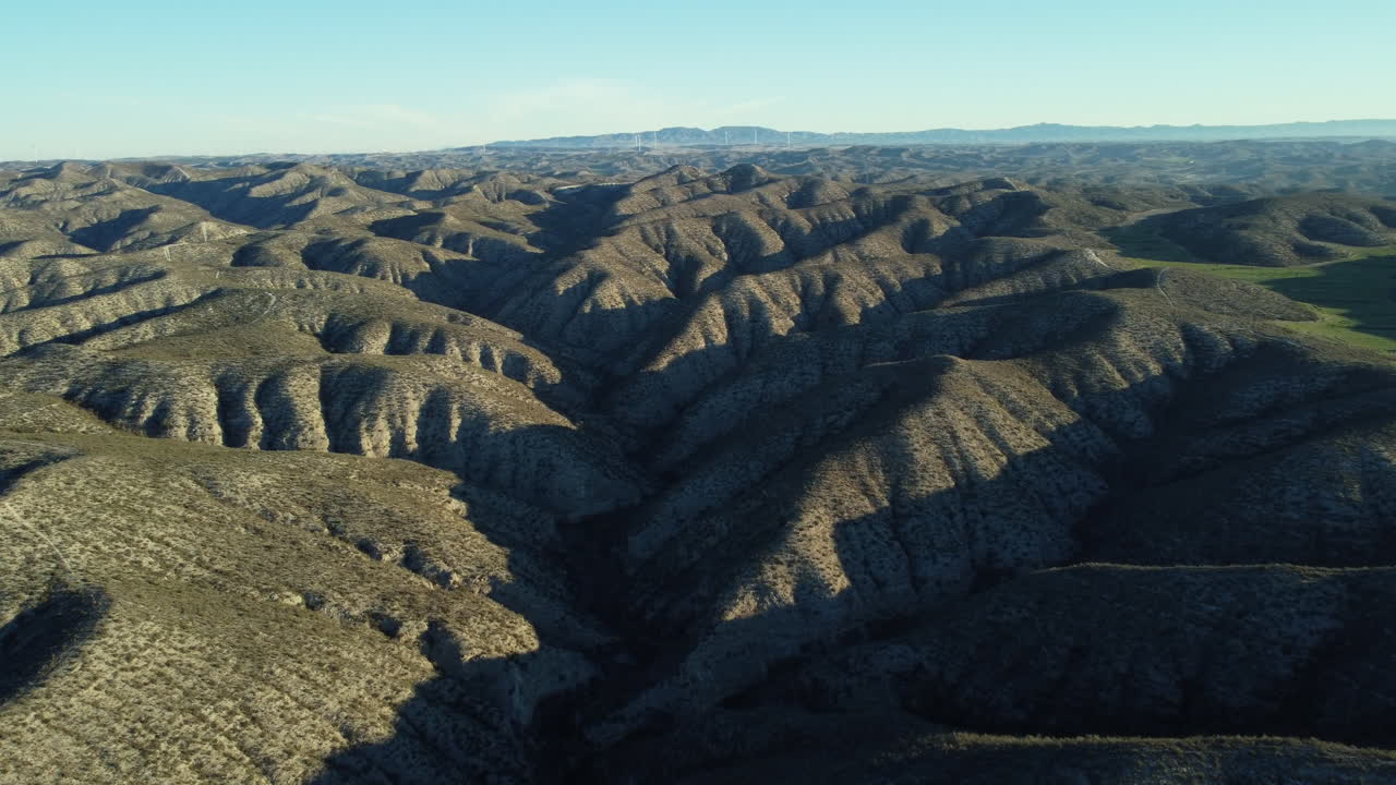 Aerial View of a Dry Mountainous Landscape with Valleys and Wind Farm