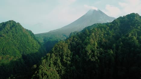 volcán merapi con dos colinas en primer plano y cubierta de denso bosque