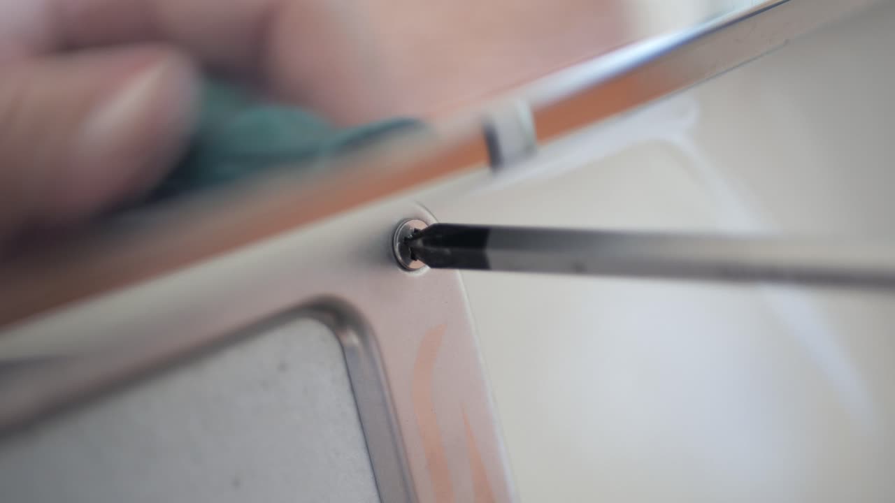 자동차 번호판에 스크루드라이버로 나사를 조이는 기계공을 가까이서 봅니다.