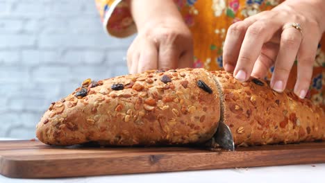 woman cutting a loaf of whole grain bread