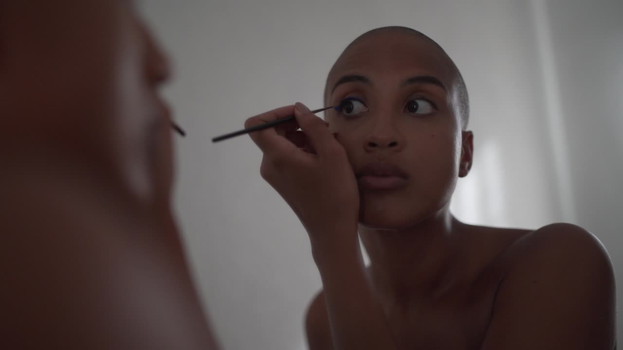 Serious black woman doing makeup at home