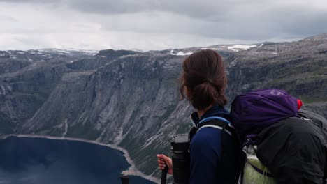 woman hiker looks at dramatic cliffs above fjord in norway, evoking awe and solitude